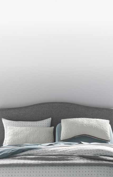 A variety of pillows in front of a grey upholstered headboard, how to choose a pillow that's right for you, link to shop all pillows