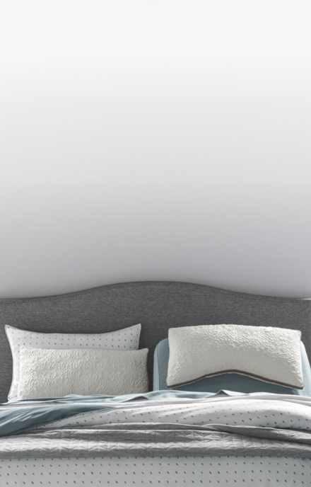 A variety of pillows in front of a STONE_300 upholstered headboard, how to choose a pillow that's right for you, link to shop all pillows