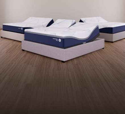 Three adjustable beds with blue‑and‑white mattresses displayed in a bright room, with the word ‘new’ repeated on the back wall.