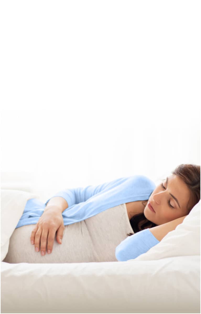 Pregnant woman sleeping on her side with her head resting on a pillow