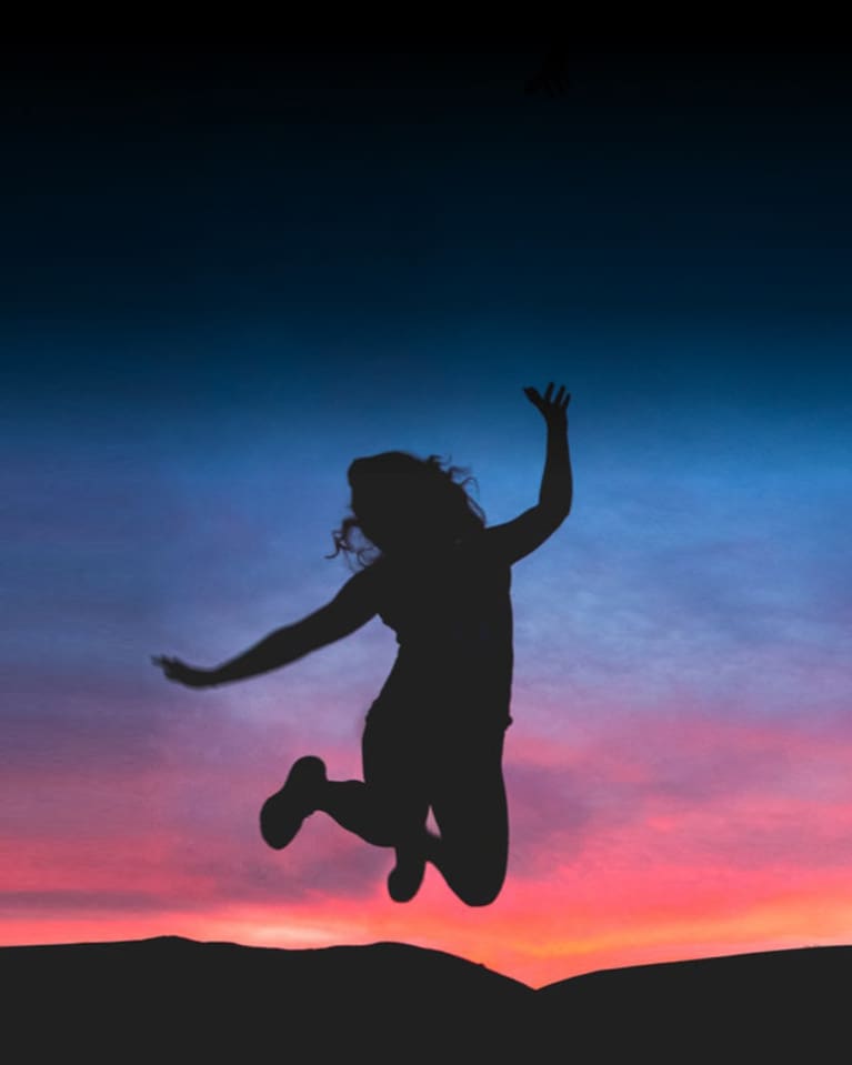 woman jumping in front of sunset