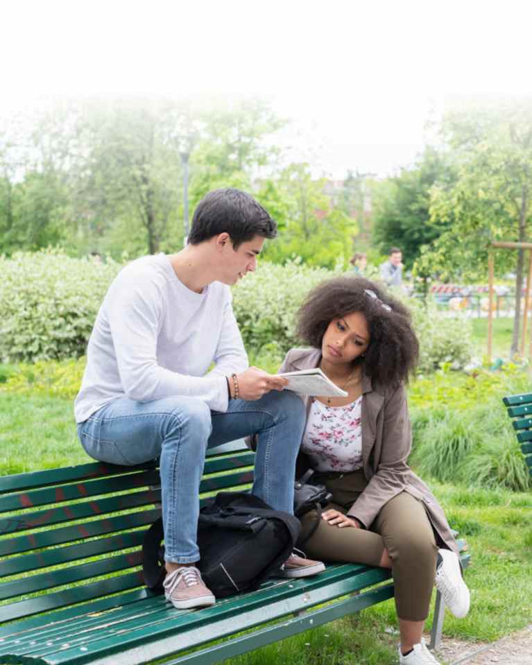 two teens sitting on bench studying