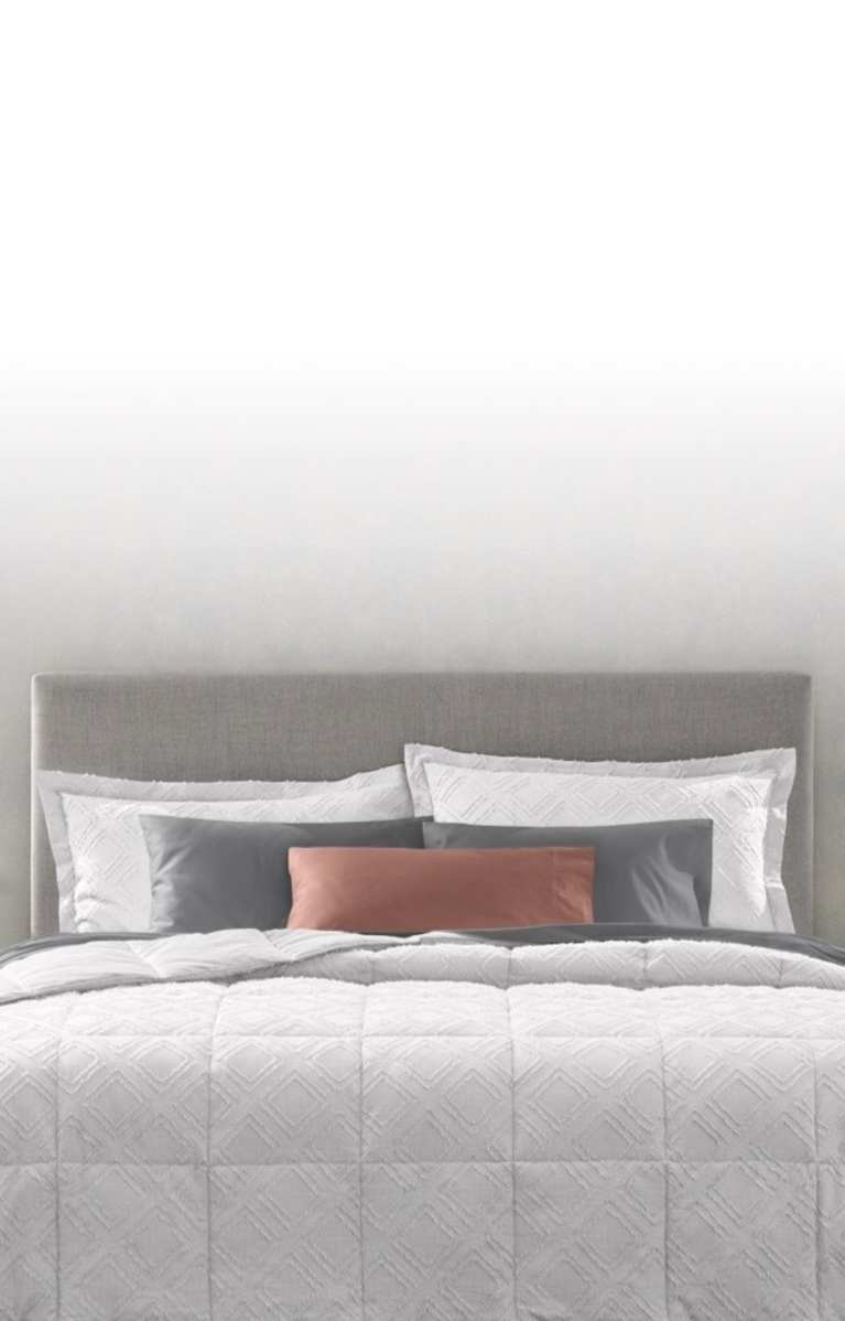 Image of head of dressed bed, Comforter vs. Duvet Guide, text reads: learn the difference and how to create a cozy, individualized retreat, link to shop now