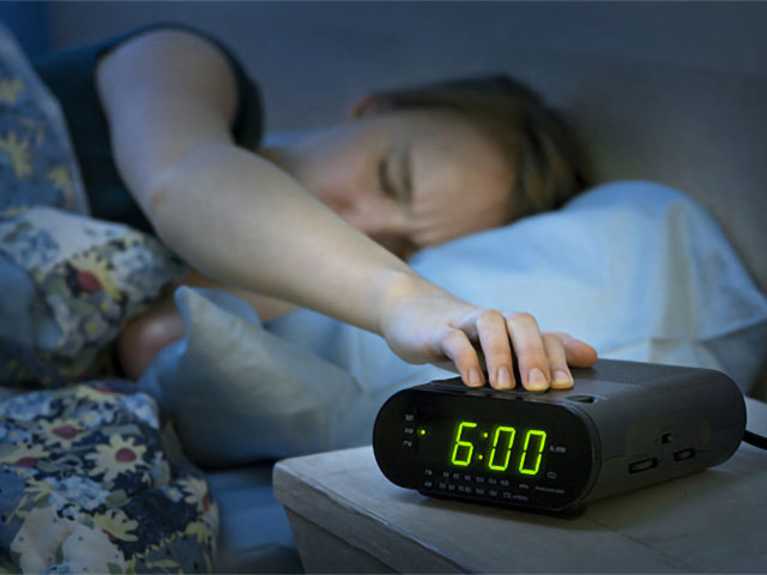 Women snoozing alarm clock
