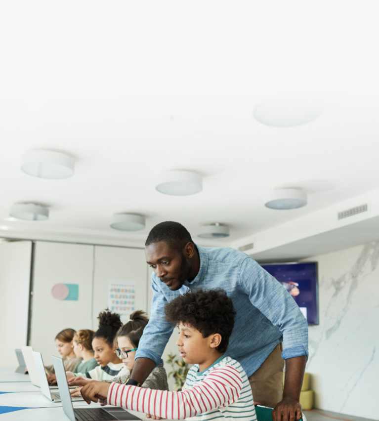 teacher holding tablet in front of classroom