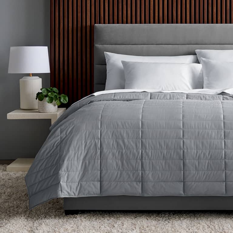 True Temp Weighted Blanket in soft rose on dressed bed that adapts to your ideal temperature throughout the night 