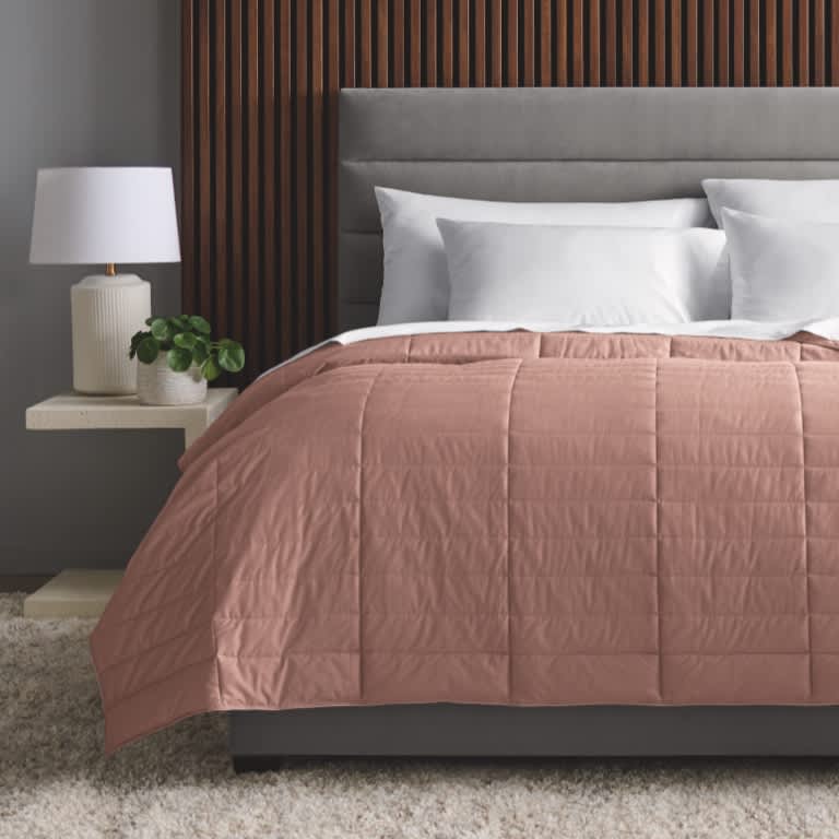 True Temp Weighted Blanket in soft rose on dressed bed that adapts to your ideal temperature throughout the night 