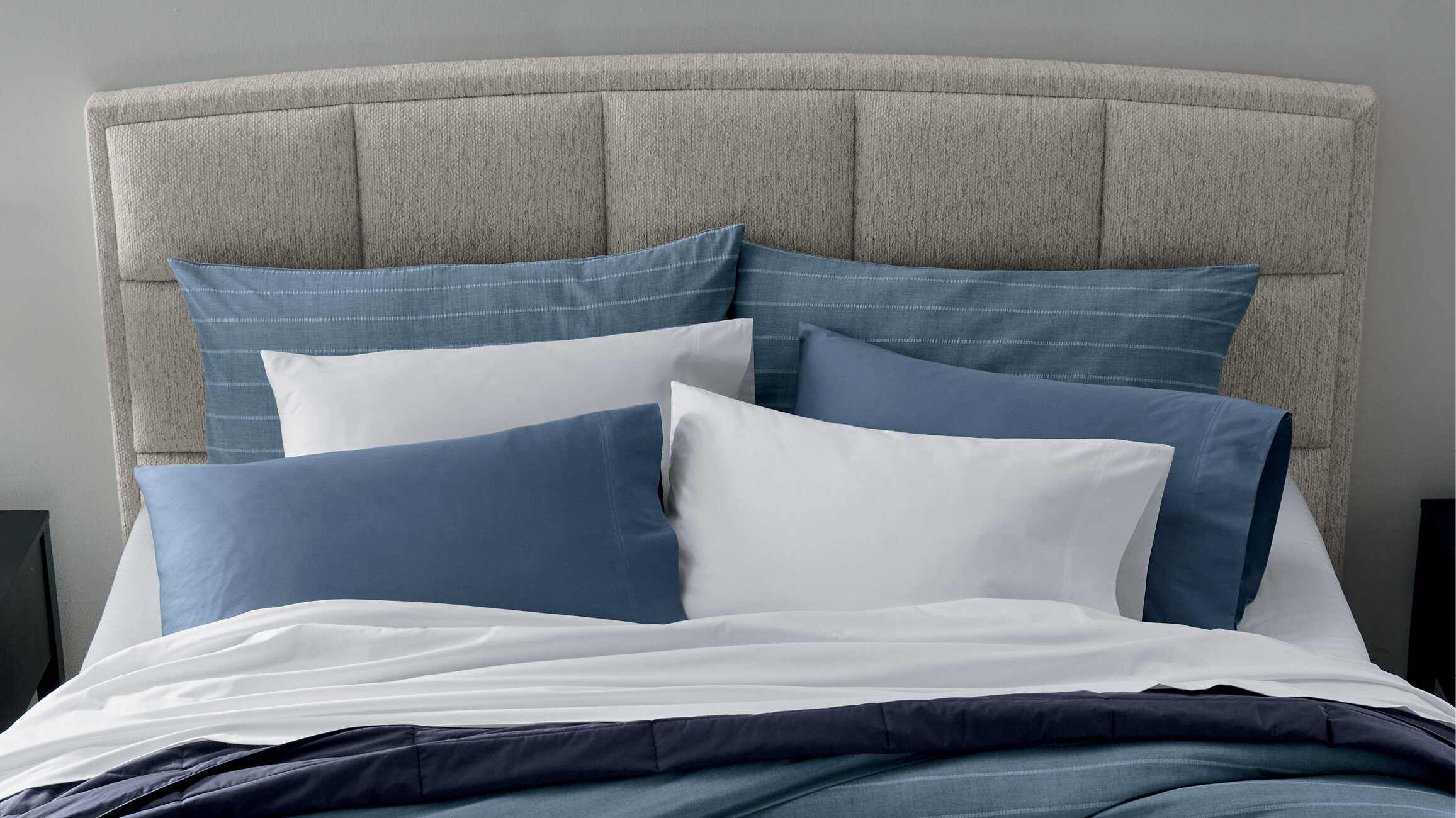 Quality & Craftsmanship - Headboard view with several blue pillows and duvet set.