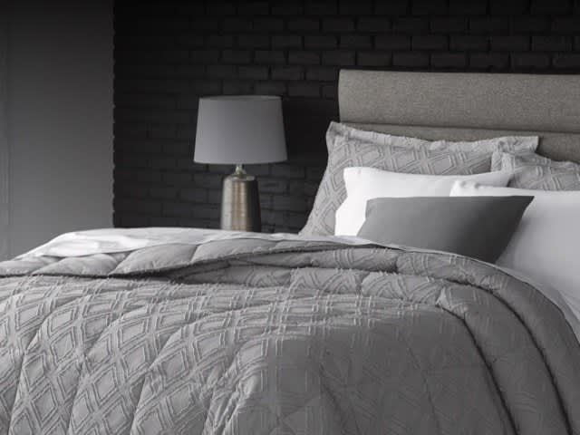 Comforter vs. duvet explained, image of dressed bed, text reads: Not sure the difference between a comforter and a duvet? A comforter is a thick blanket-like bedding layer with an insulated filling. A duvet insert is essentially the same as a comforter; however comforters are often available in colors and patterns, while duvet inserts are typically white and are paired with a removable duvet cover. The duvet cover helps protect your comforter or duvet insert and adds beauty to your bed.