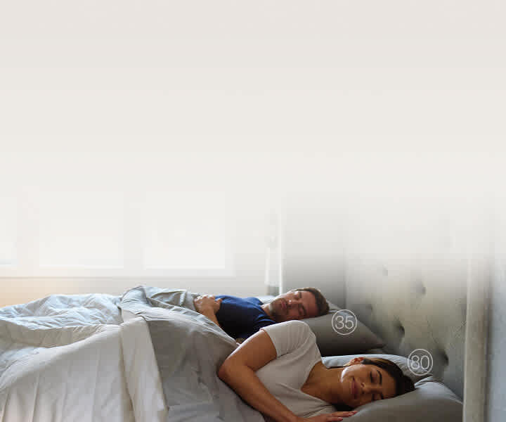 Man and woman sleeping well on a smart bed with white bedding and a grey headboard