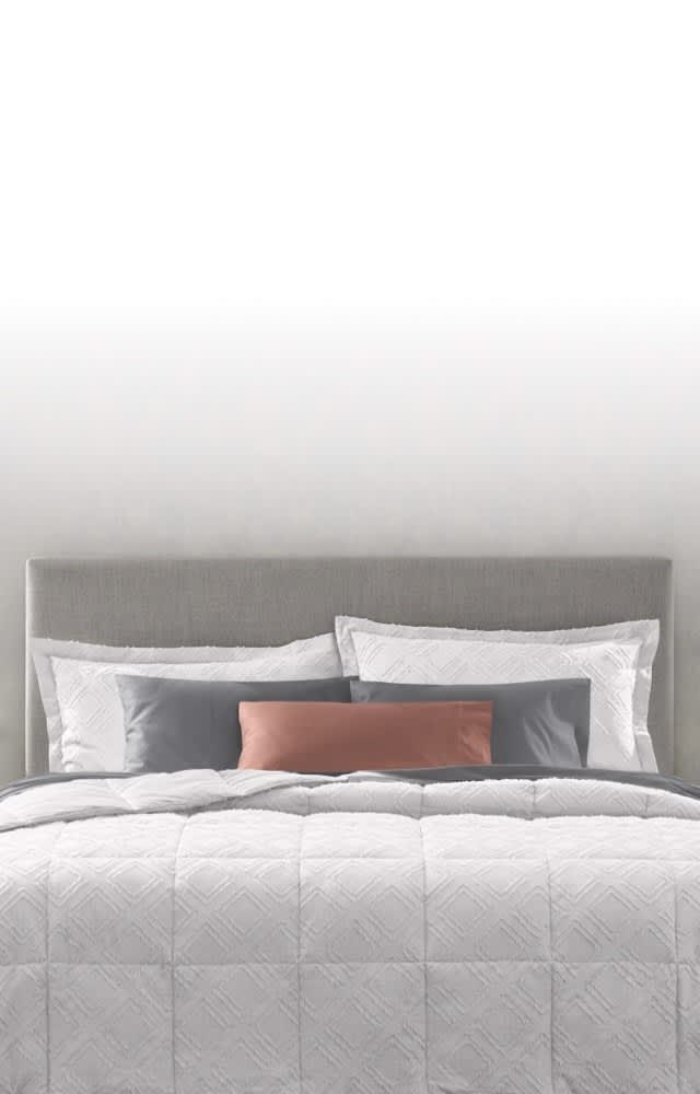Image of head of dressed bed, Comforter vs. Duvet Guide, text reads: learn the difference and how to create a cozy, individualized retreat, link to shop now