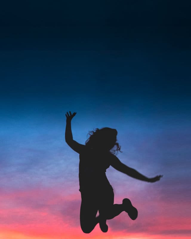 woman jumping in front of sunset